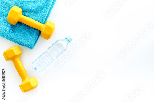 Fitness background. Dumbbells, towel and water on white background top view copyspace
