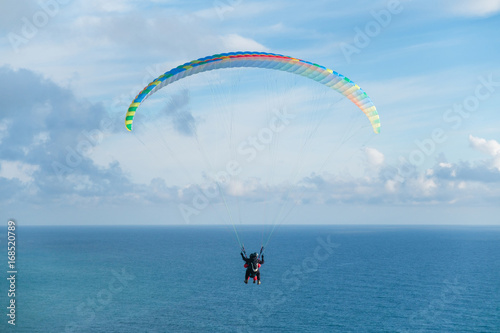 Flying a tandem paraglider over the sea with views of the horizon