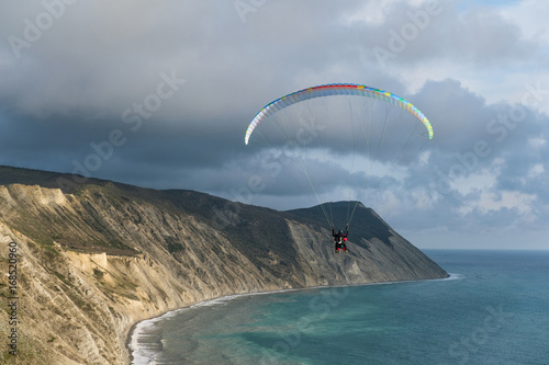 Flying tandem paragliders over the sea and near the mountains, beautiful landscape view