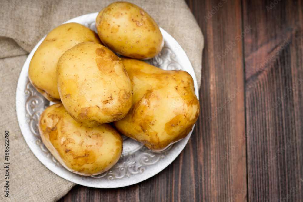 Raw potatoes on a brown wooden background Raw potatoes on a brown wooden background
