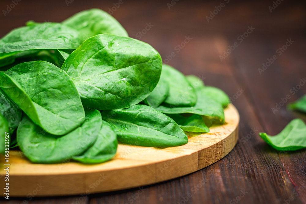 Fresh juicy spinach leaves on a wooden brown table. Natural products, greens, healthy food, vitamins. Fresh juicy spinach leaves on a wooden brown table. Natural products, greens, healthy food, vitamins.