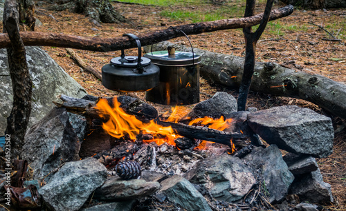 Kettle with food on bonfire in forest during evening camping