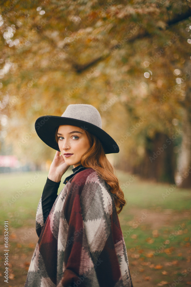 Woman in coat with hat and scarf in autumn park 