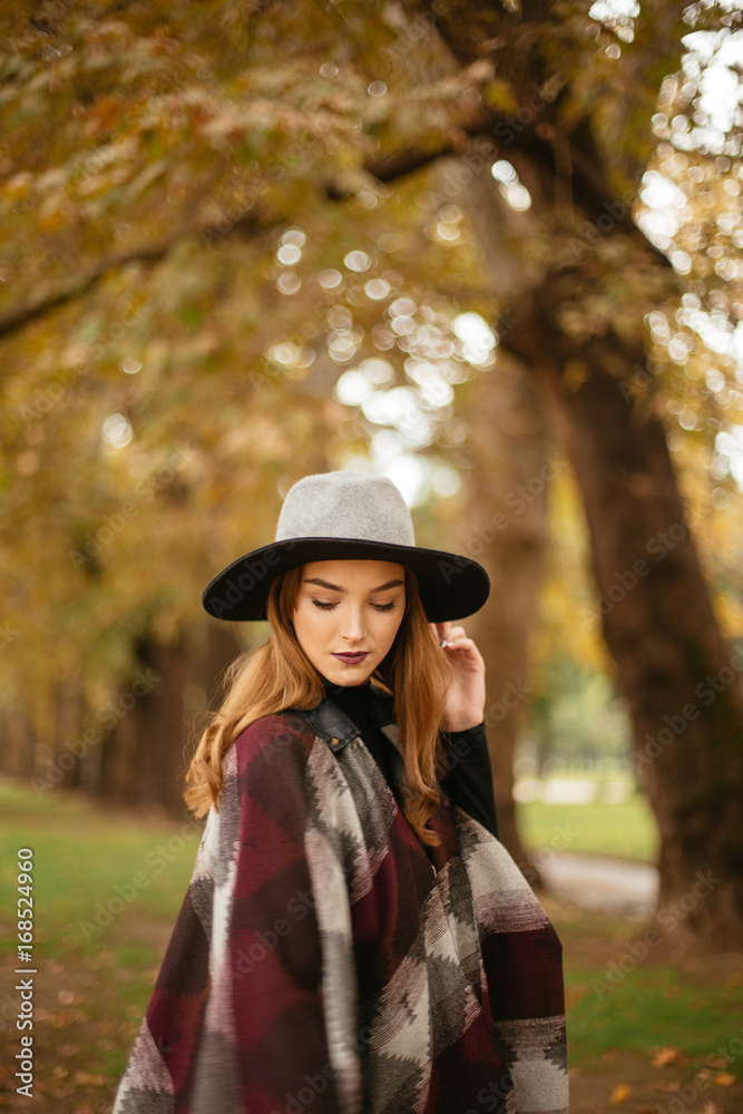 Woman in coat with hat and scarf in autumn park 