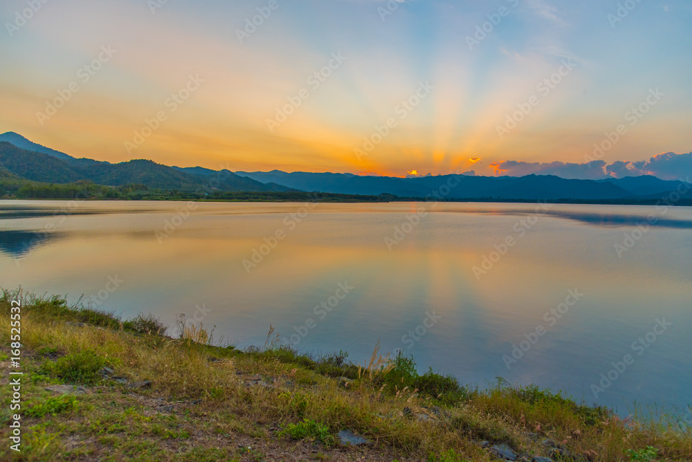 Dramatic view and magic sunbeam at sunset, mountain background. Tranquil panorama landscape of Yang Choom Reservoir, Kui Buri, Prachuap Khirikhan, Thailand.