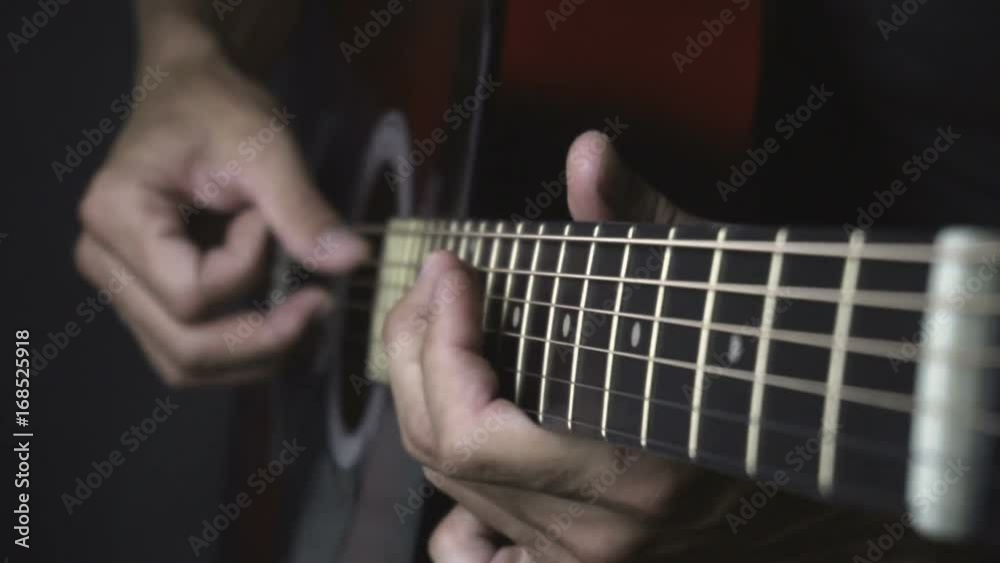Man playing acoustic guitar on black background with fingers in slow motion Man playing acoustic guitar on black background with fingers in slow motion