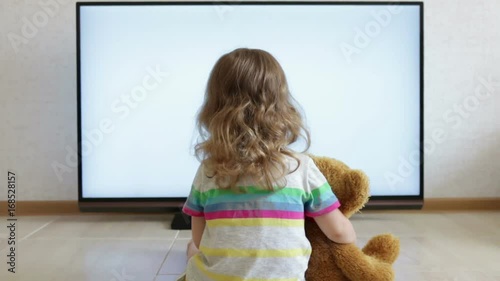 Little child is sitting on the floor and watching TV