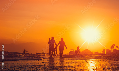 happy family and tourist silhouettes on the beach during sunsetin summer photo