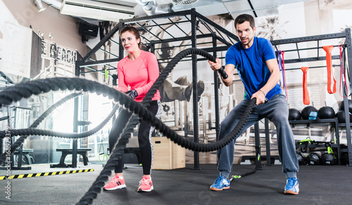 Frau und Mann im Fitnessstudio mit battle rope