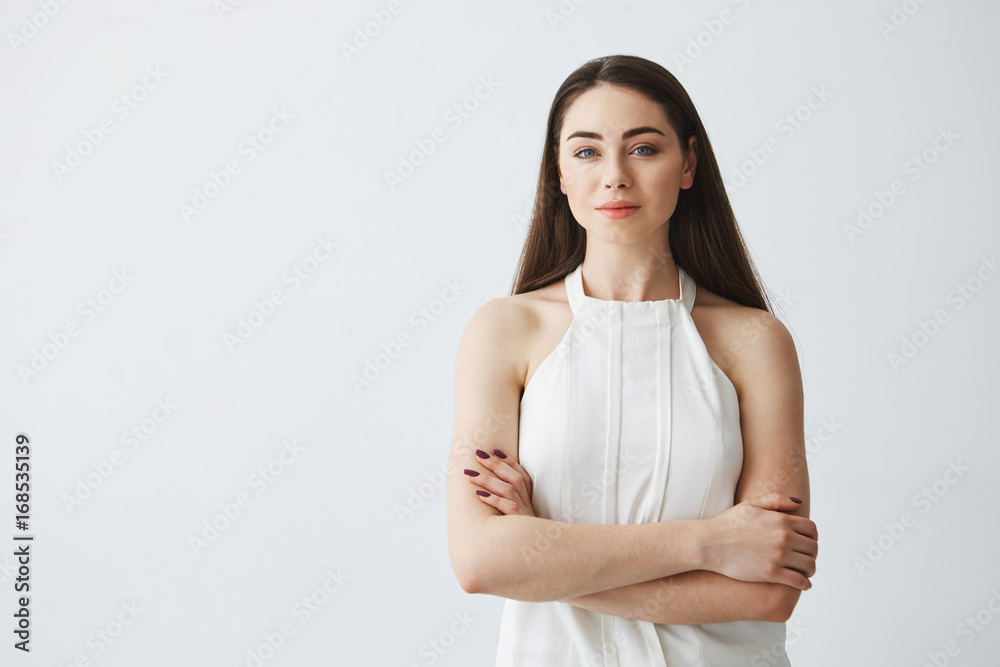 Portrait of young beautiful businesswoman looking at camera with crossed arms over white background. Portrait of young beautiful businesswoman looking at camera with crossed arms over white background.