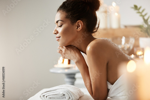 Fototapeta samoprzylepna Portrait of pleased african girl relaxing with closed eyes in spa salon.