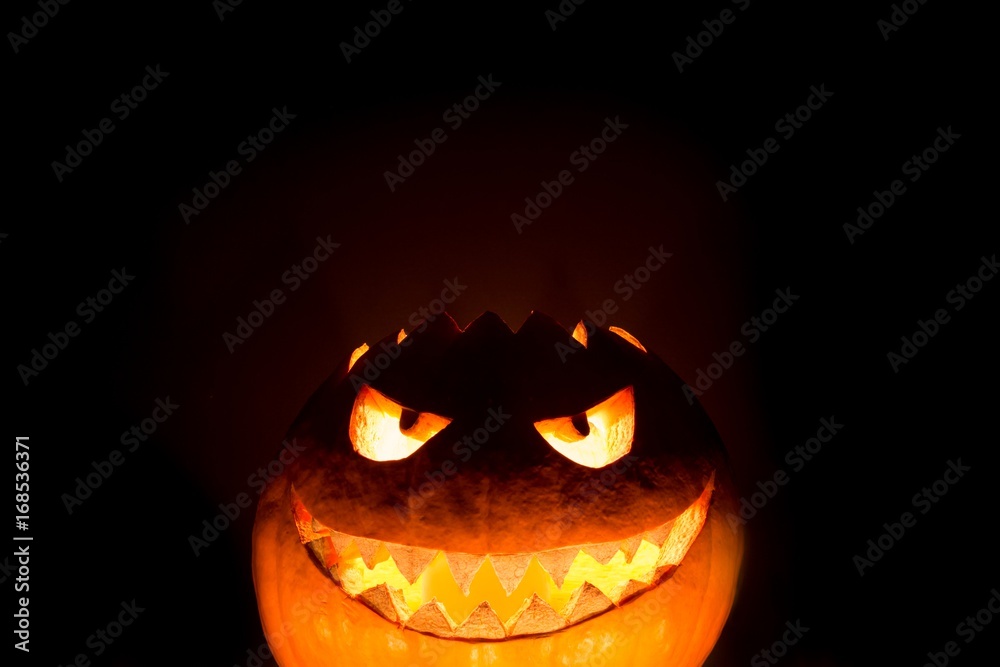 Fototapeta premium Bottom halloween pumpkin smile with hot burning fire eyes mouth. Big spooky helloween symbol has a glowing mad face and smiling with sharp teeth and bad look. Black orange nightmare of October 31st