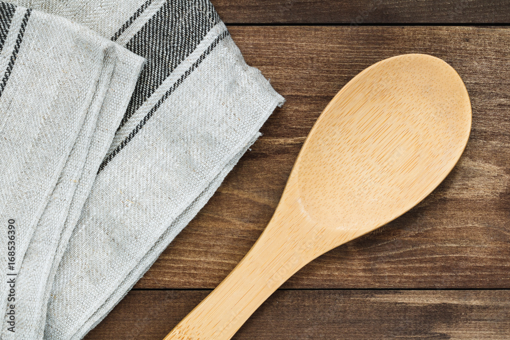 Top view on a rustic wooden big spoon and linen towel. Cooking concept.