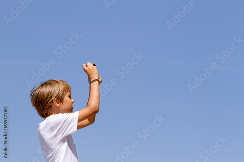 Young boy with a digital camera against blue sky