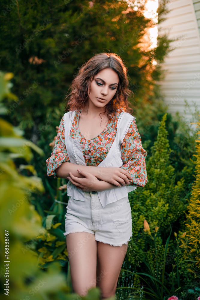 Beautiful young woman in romantic styled white shorts, blouse and vest on foliage background. Perfectly retouched. Beautiful young woman in romantic styled white shorts, blouse and vest on foliage background. Perfectly retouched.