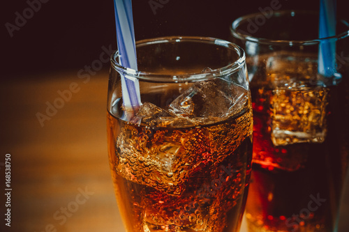 Fototapeta Beautiful cold drink of Cola with ice cubes with a boiler straws in glasses on w
