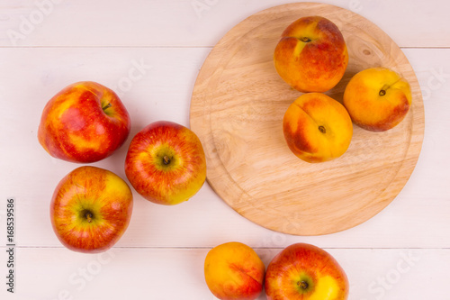 Ripe apples and peaches on a wooden table. Ripe fruit on a light background - top view.