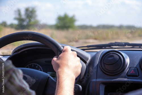 Men hands on the wheel of a car.