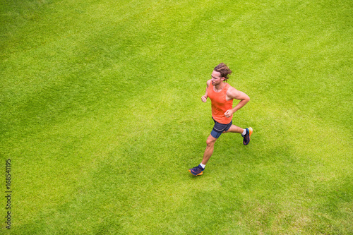Jogging man training cardio morning run routine on grass park summer. Running runner active lifestyle - View from above. © Maridav