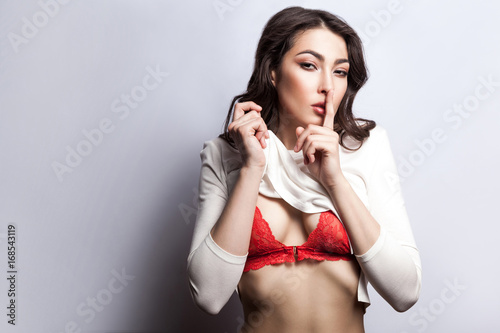 Secret between us, do not tell anyone. Sexy young fashion model undressing and looking at camera