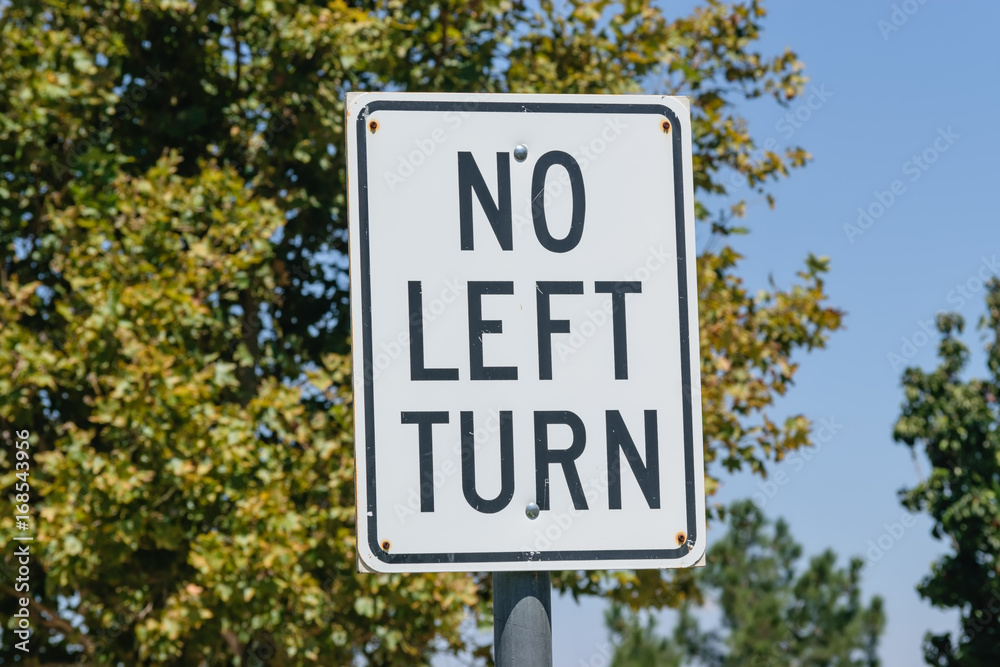 No left turn sign with trees and blue sky background