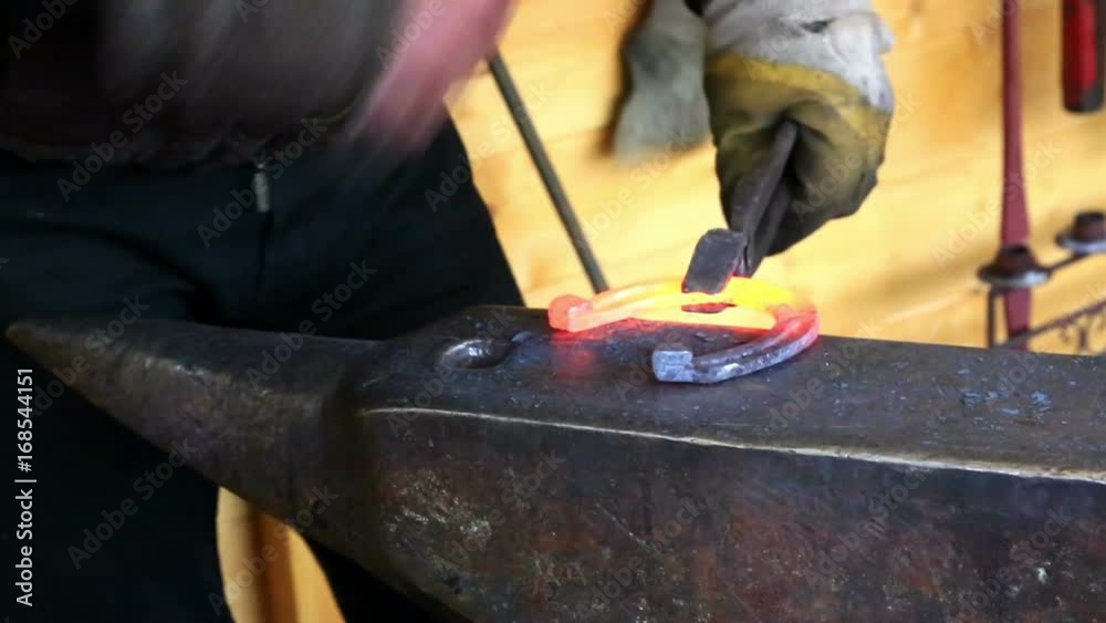 Blacksmith forges a horseshoe on the anvil Blacksmith forges a horseshoe on the anvil