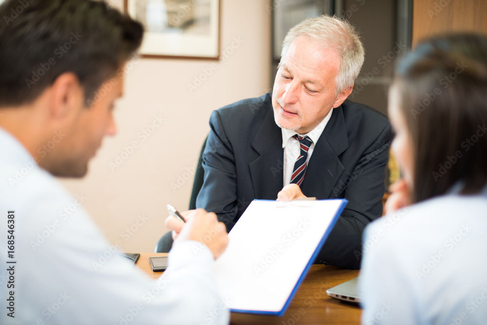 Businessman showing a contract to make a man put a signature on it Businessman showing a contract to make a man put a signature on it