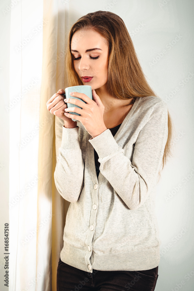 Beautiful casual caucasian woman standing by the window with hot Beautiful casual caucasian woman standing by the window with hot