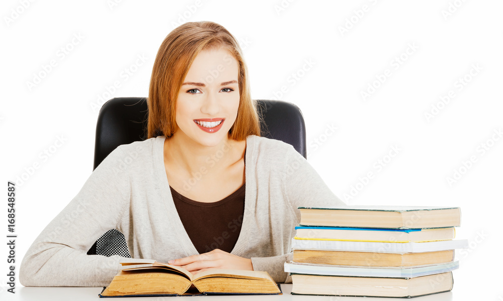 Beautiful student woman sitting by the desk with books and learn Beautiful student woman sitting by the desk with books and learn