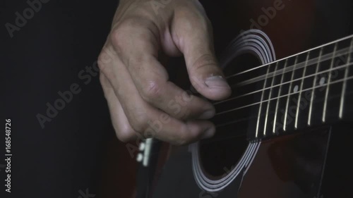 Man playing acoustic guitar on black background with fingers in slow motion