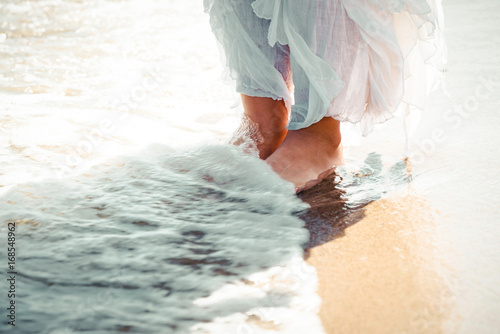 Pictore of feet on a beach and water. photo