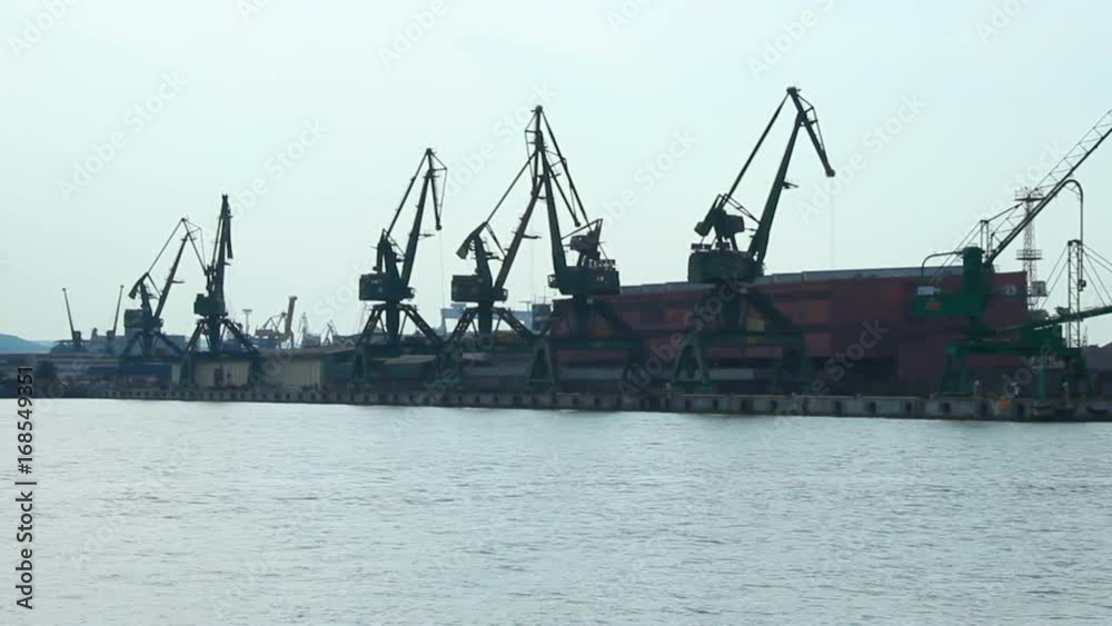 Boat moving by seaside port cranes and storehouses, freight transportation Boat moving by seaside port cranes and storehouses, freight transportation