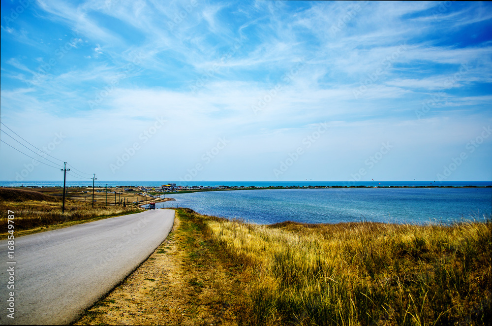 landscape of a sea spit with an automobile road and a beautiful blue sky landscape of a sea spit with an automobile road and a beautiful blue sky
