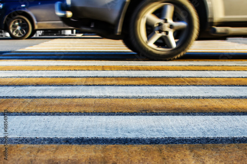 Yellow and white stripes on the asphalt. Cars on the pedestrian crossing
