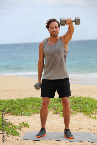 Картината върху платно Fitness man lifting dumbbells on beach doing Front Dumbbell Raise i