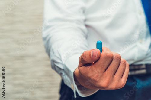 Male businessman holds in his hand blue pill