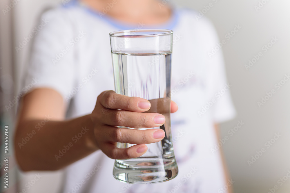 The hands of a beautiful woman holding a glass of water on a white background. The hands of a beautiful woman holding a glass of water on a white background.