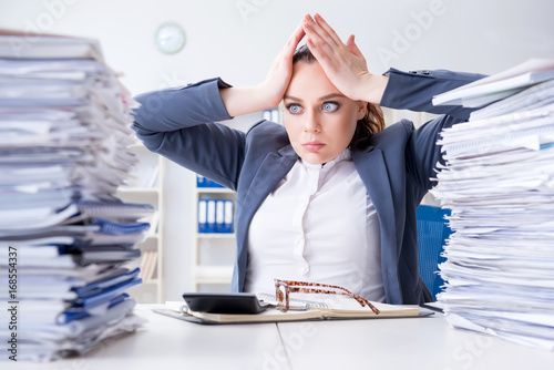 Tired businesswoman with paperwork workload photo