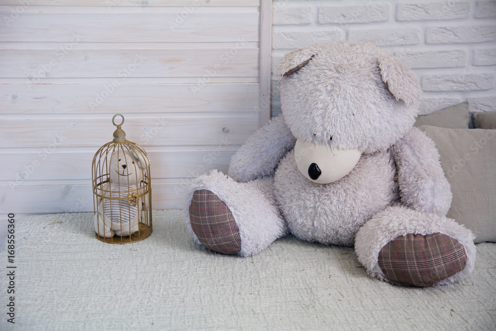 Teddy bear sitting on a bed next to a caged little bear Stock Photo ...