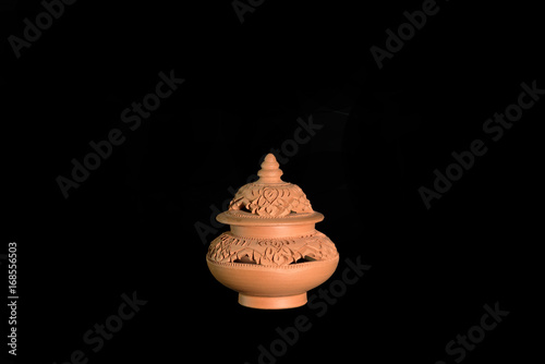 Isolated terracotta stove for aromatherapy on black background photo