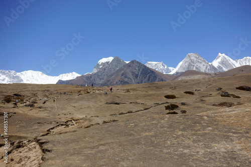 Tourists walk along the high plateau to the snowy peaks