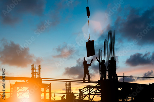 Silhouette construction industry team safely to work load concrete building according to set goal over blurred background sunset pastel for industry background.