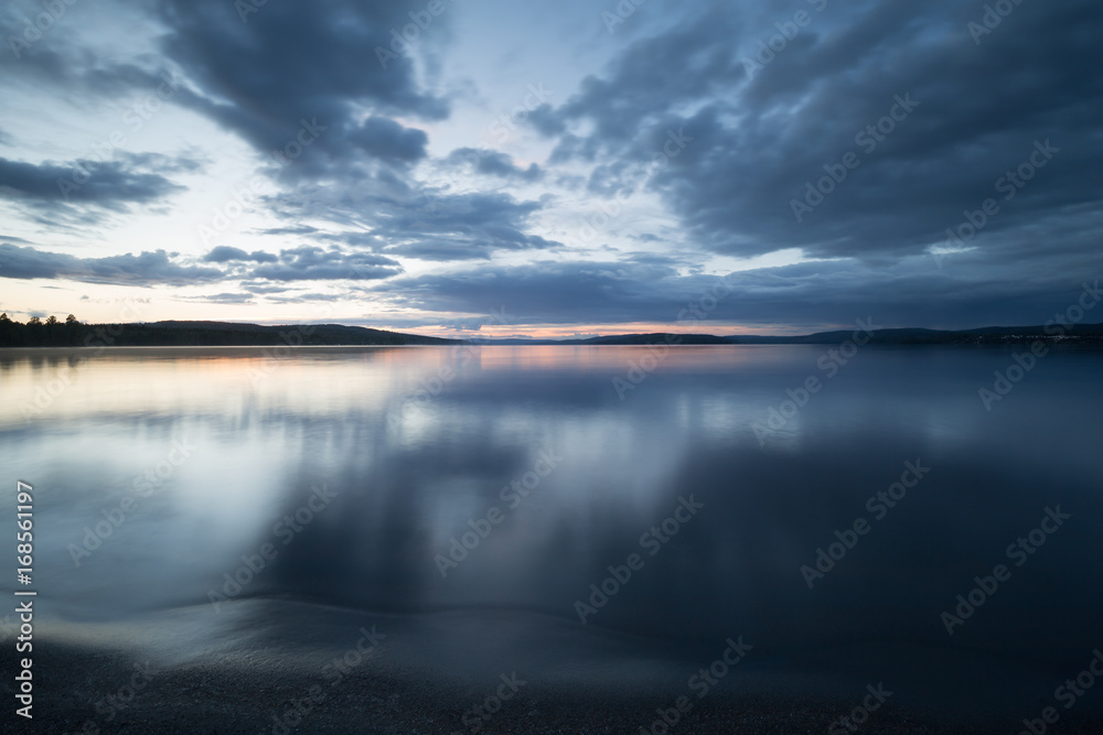 Beach of a calm swedish lake photographed in twilight