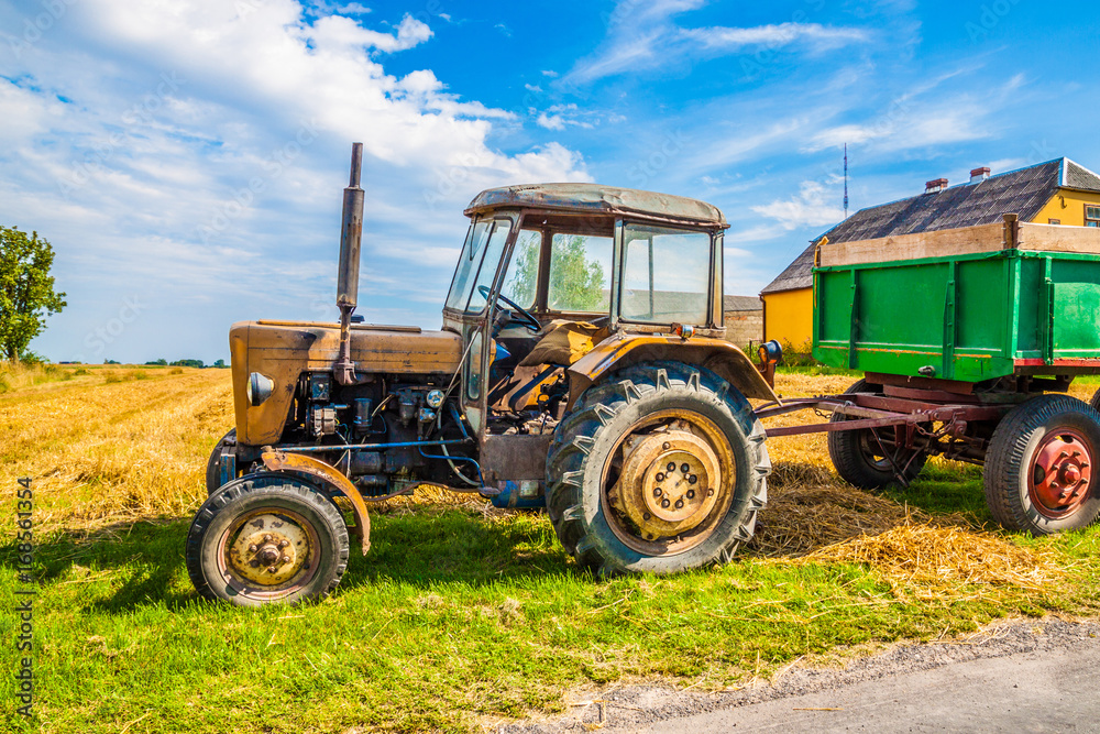 Old red rusty farm tractor at the edge of a field Old red rusty farm tractor at the edge of a field