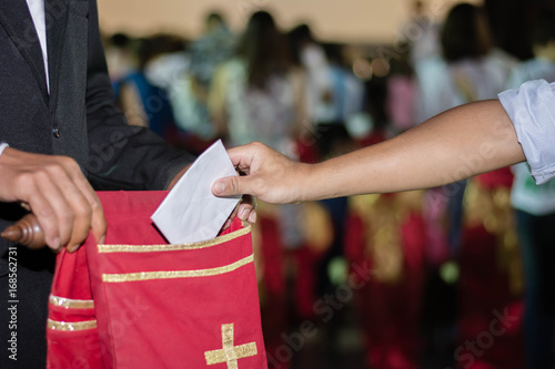 Fotografie people putting tithing into Velvet offering bag in church