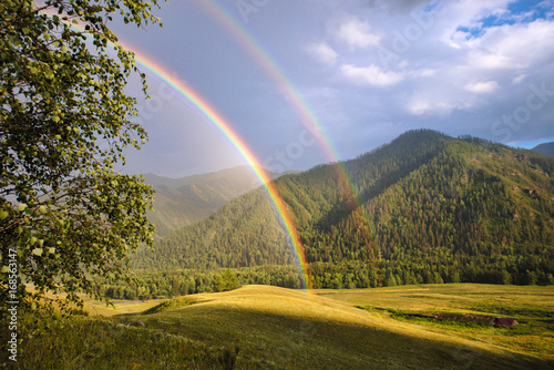 Fotografie, Obraz panoramic view of bright rainbows over railway rails between green hills