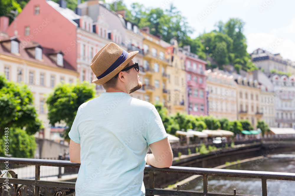 Back view of happy stylish tourist on Czech Republic. Handsome man travelling in Europe.