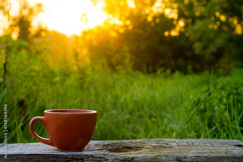 Morning cup of coffee on wooden table at sunrise Morning cup of coffee on wooden table at sunrise