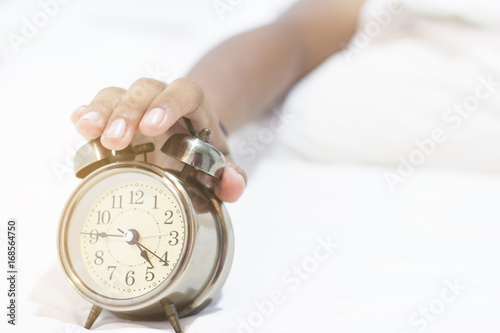 Girls hands on the clock on a bed of white. The dawn of a new day.
