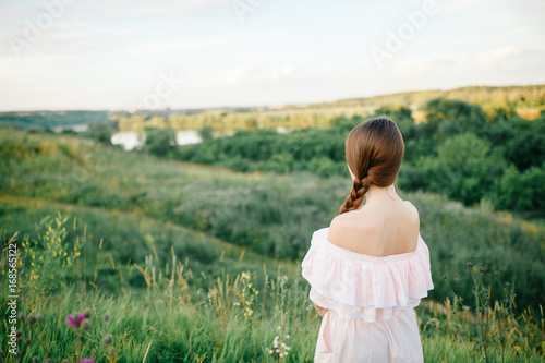 Beautiful girl walking on the grass field on the evening sun